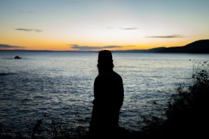 silhouette of man looking out onto the ocean at sunset