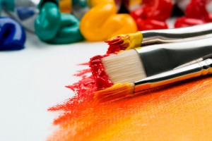 paint brushes laying on canvas with orange and red paint streaks