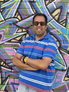Photo of Rahul Seth leaning against a colourful graffiti wall