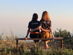 Sisters sitting on a bench facing away wearing sisterhood tshirts