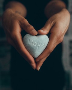 women's hands holding hope rock