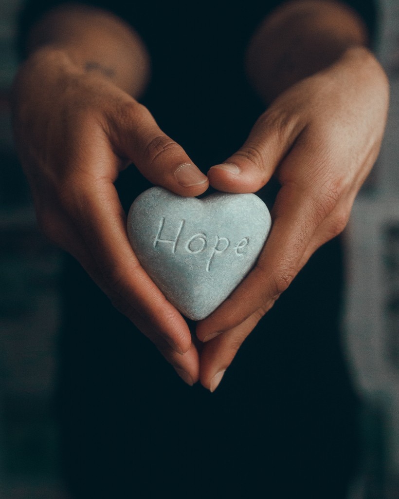 women’s hands holding hope rock